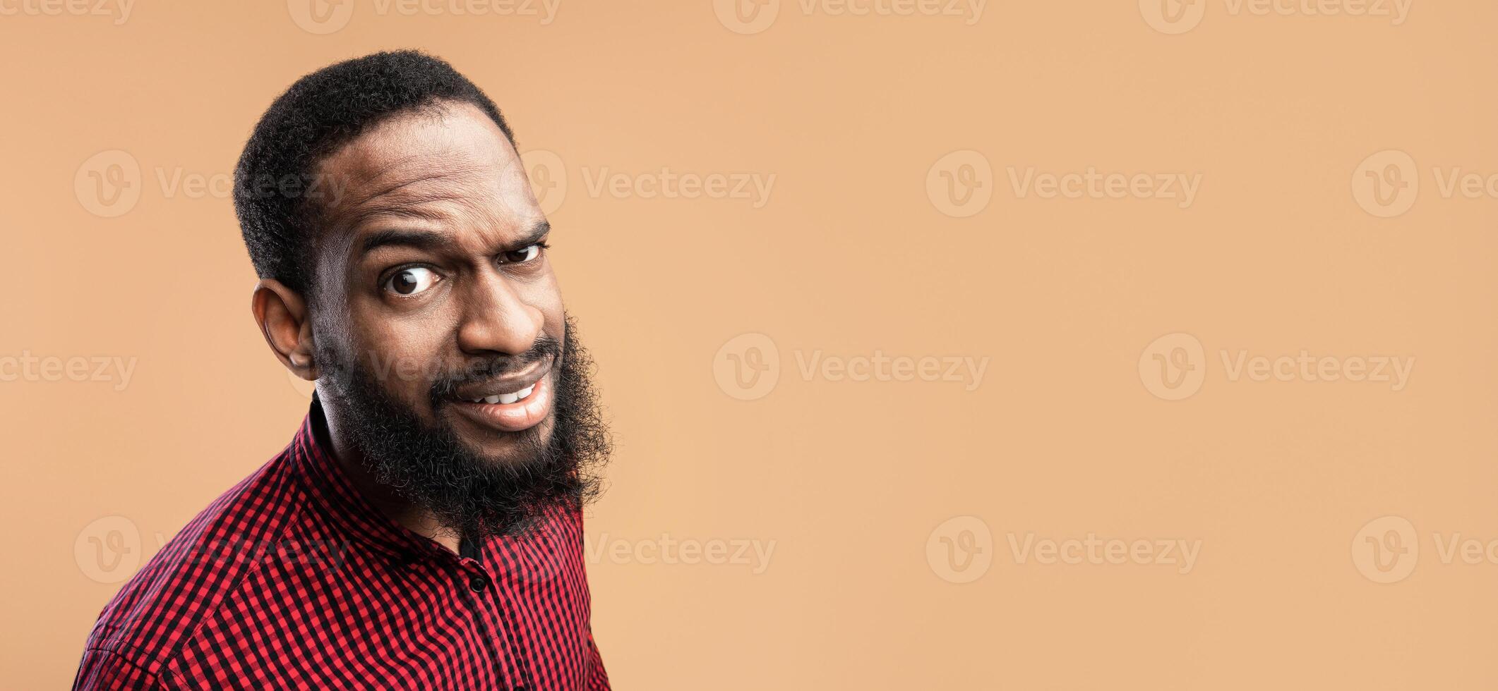 Close up headshot of confused african american man looking at camera with raised eyebrow, yellow studio wall photo