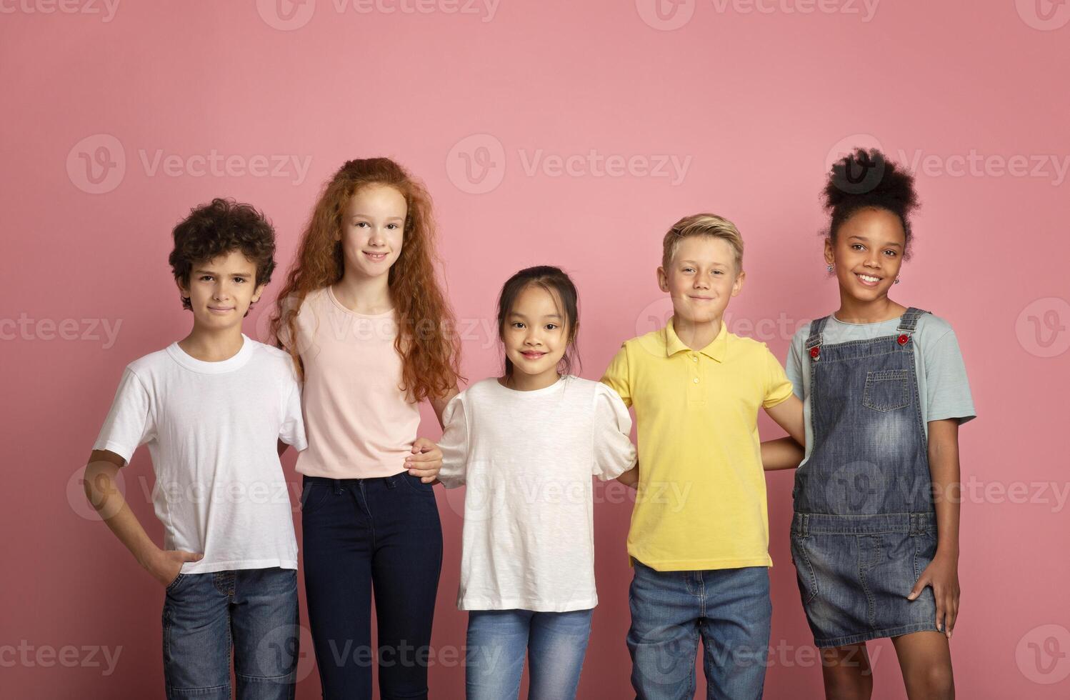 Back to school concept. Happy diverse boys and girls posing on pink background photo