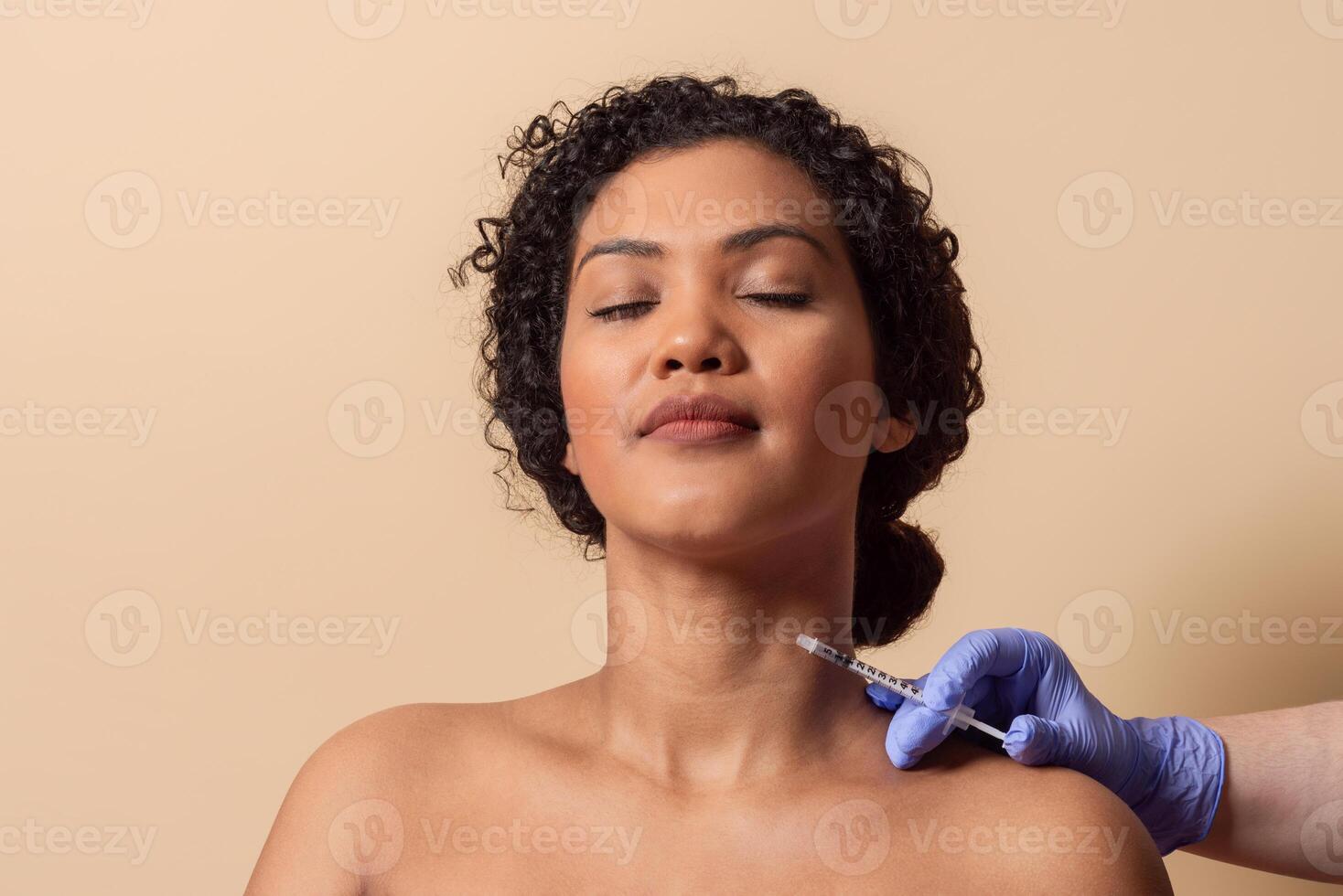 A woman sits calmly with her eyes closed while a professional administers a cosmetic injection to her neck. The peaceful environment reflects a sense of tranquility and care. photo