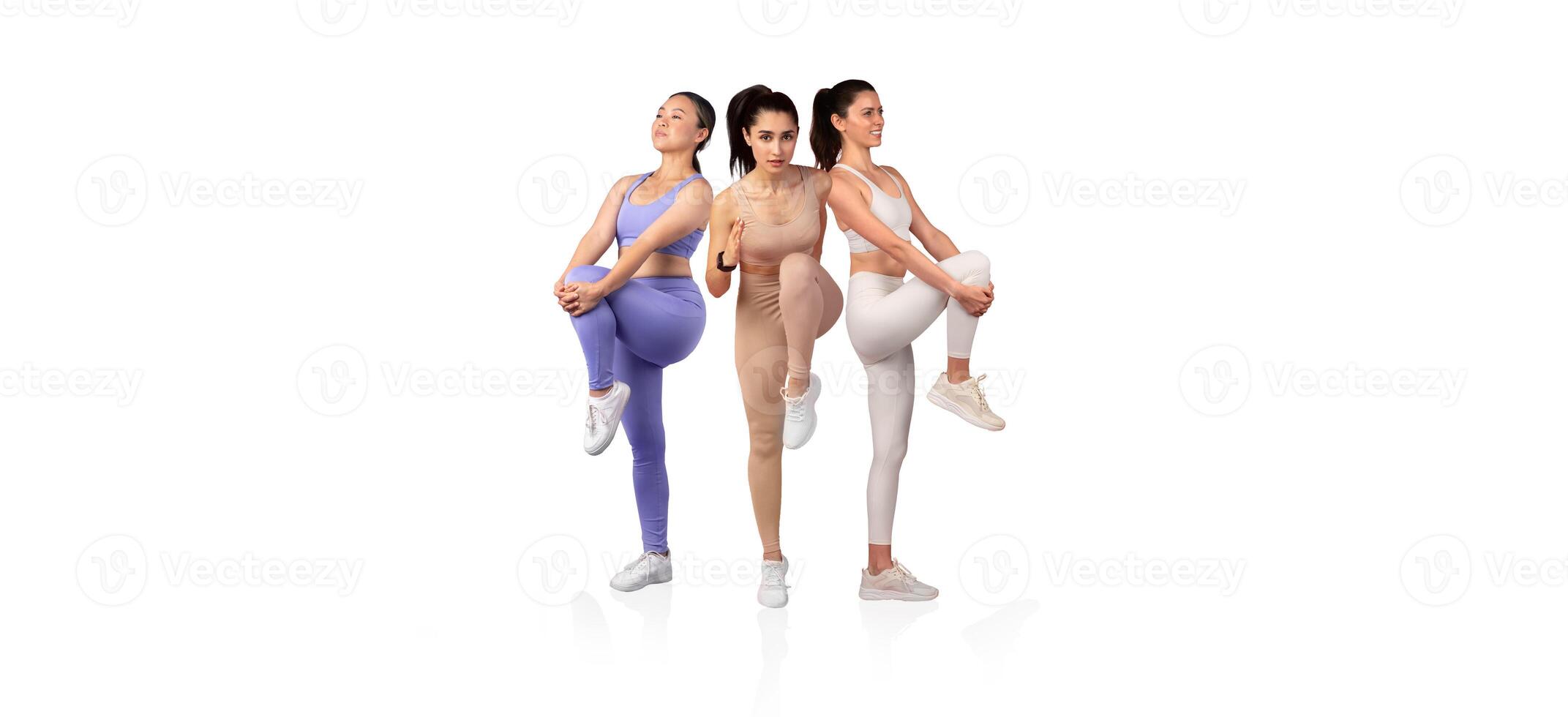 Three women in activewear showcase different fitness poses, emphasizing leg movement and core strength while engaging in a workout session in a bright, open space. photo