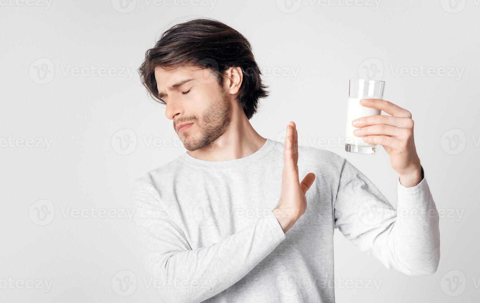 Food allergies and lactose intolerance. Man refuses of glass of milk isolated on light background, studio shot photo