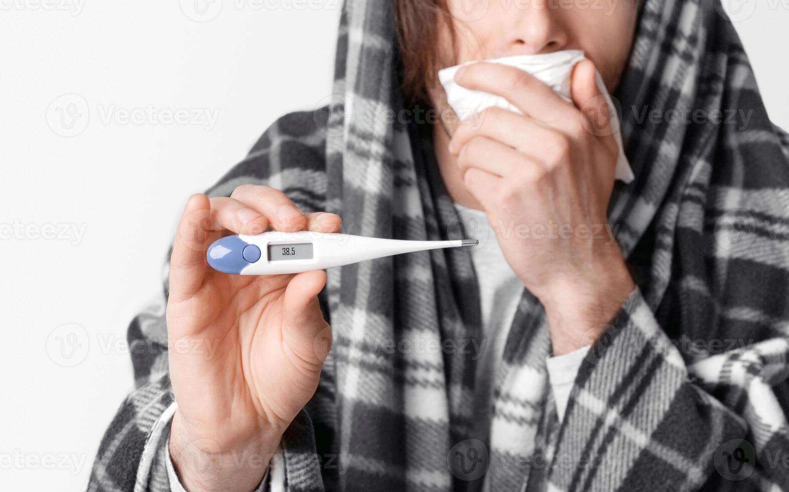 Fever and illness. Man coughs, covers his mouth with napkin and shows modern thermometer with high temperature, panorama, cropped, studio shot photo