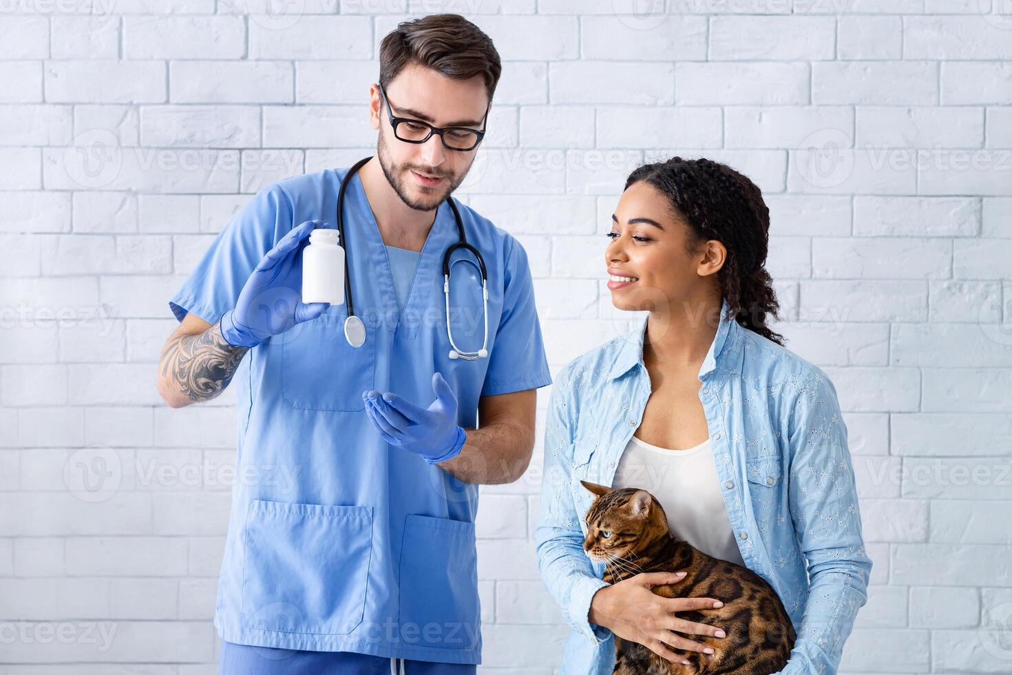 Owner of cute tabby cat and veterinary doctor with meds in animal hospital photo