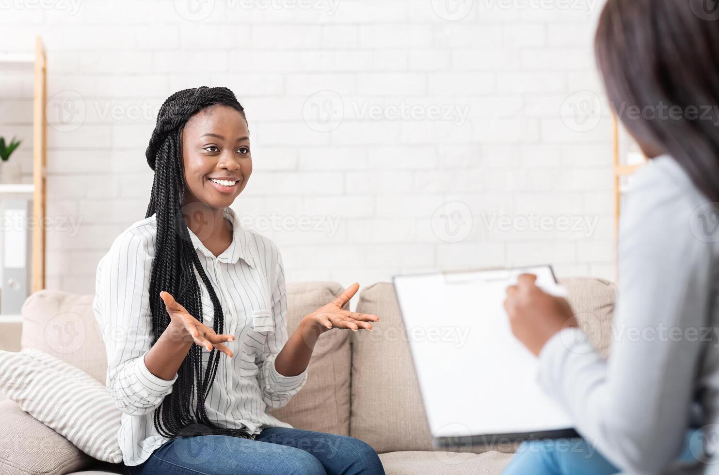 Successful therapy. Happy black female patient talking to psychologist at her office, expressing gratitude photo