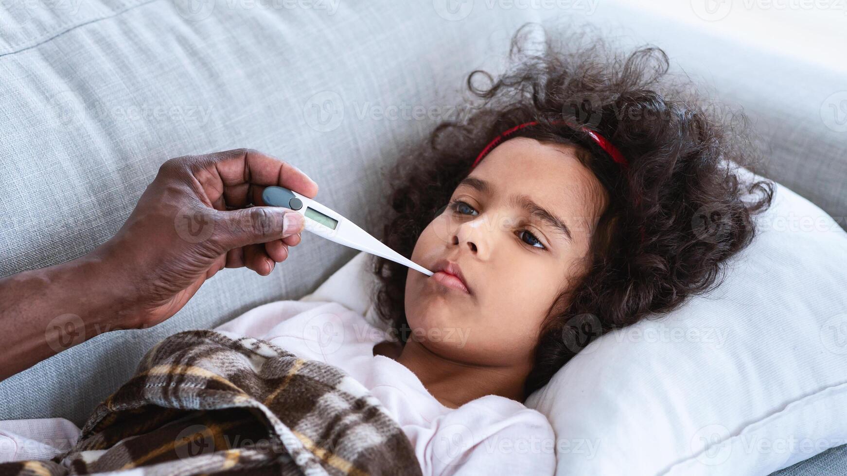 World pandemic concept. Sick little girl with high fever and her grandfather holding thermometer indoors. Panorama photo