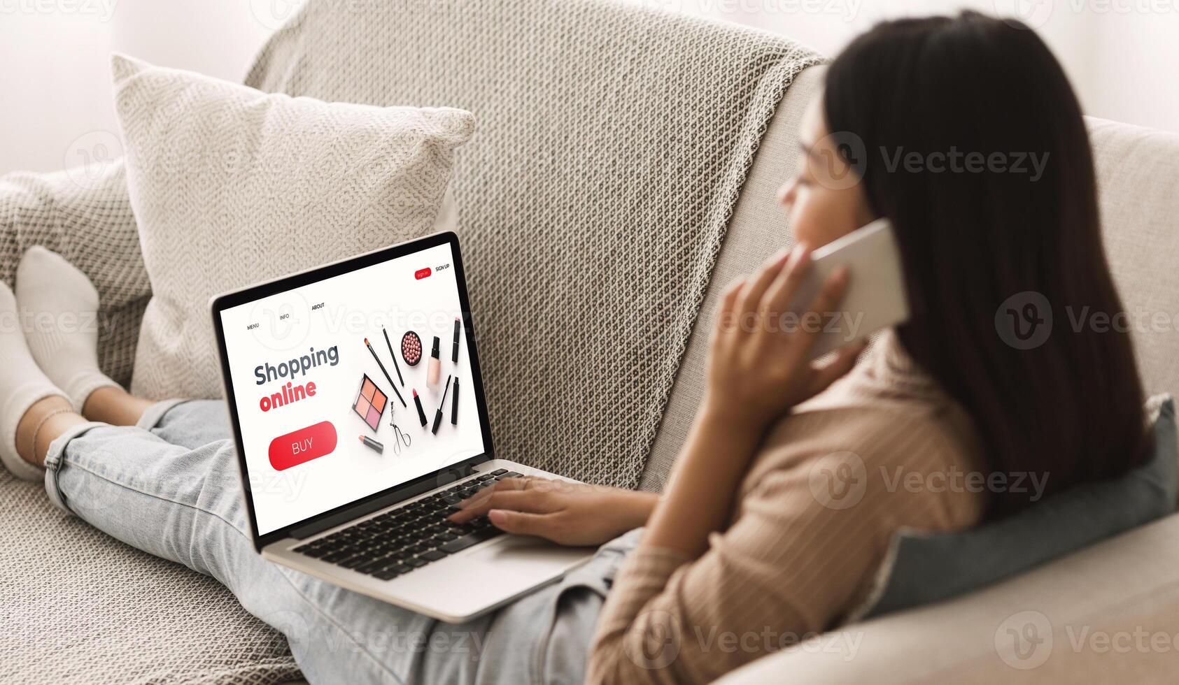 Female Shopping Concept. Back view of woman browsing online make up store, talking on phone, sitting at home photo