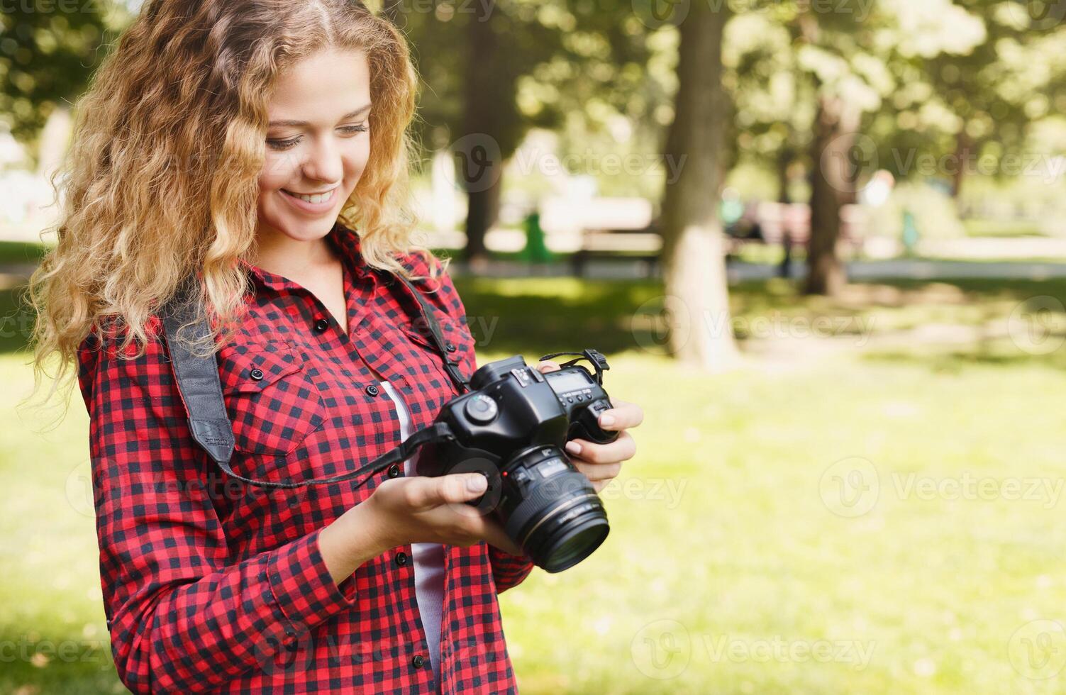 Young female student taking photos in the park with camera. Photography classes, education and remote working concept, copy space, closeup
