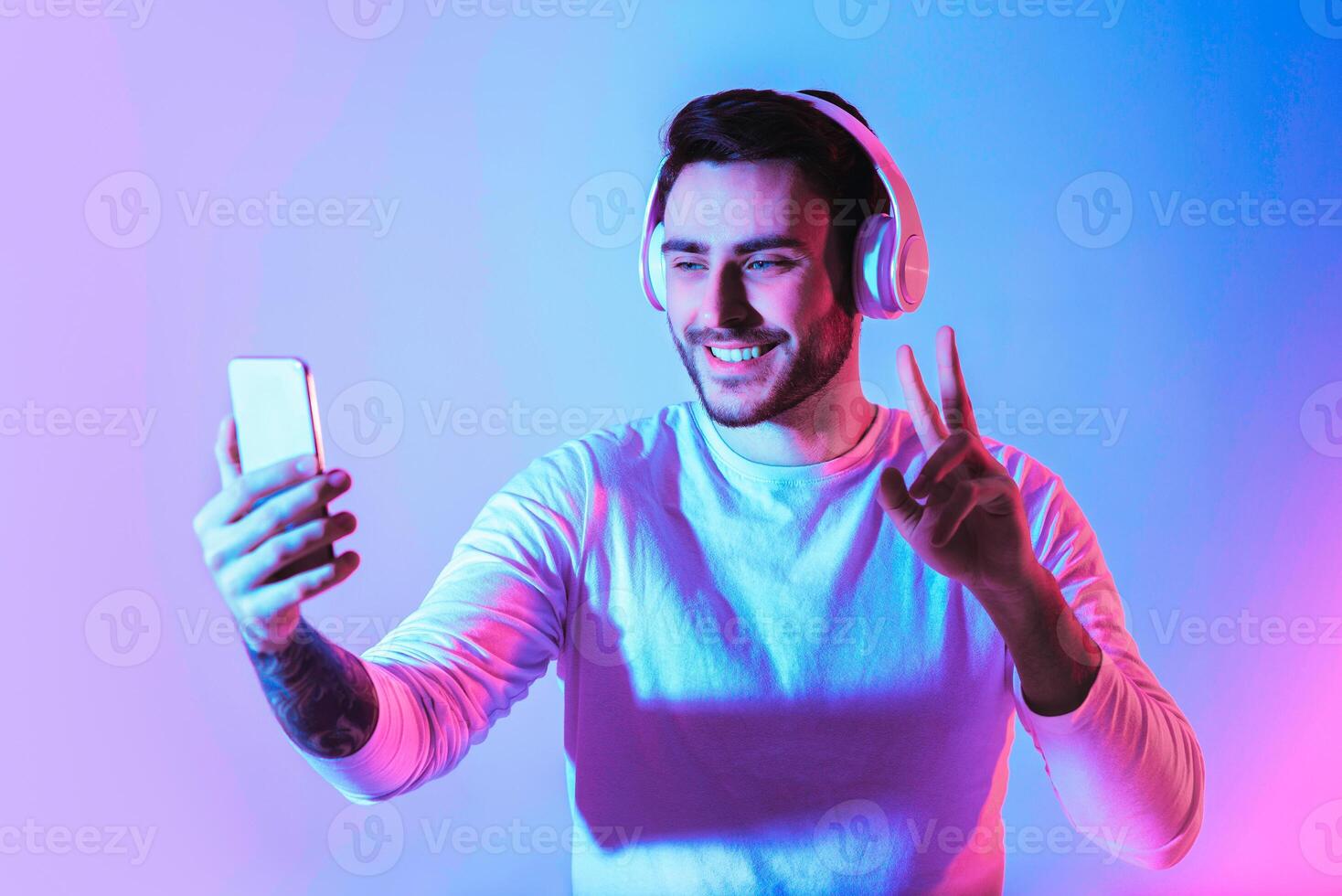 Communication online. Smiling guy showing peace sign in smartphone photo