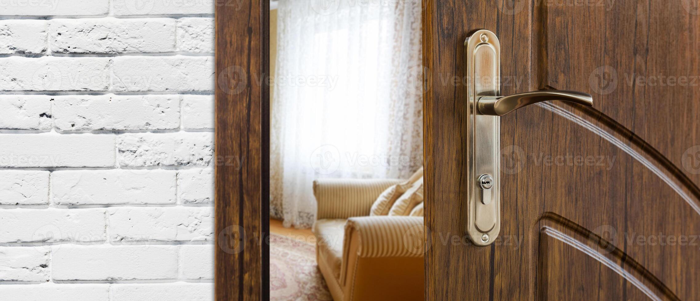 Half opened door handle closeup, entrance to a living room. View of sofa. Welcome, privacy concept. Door lock with keys, white brick wall, modern interior design. photo
