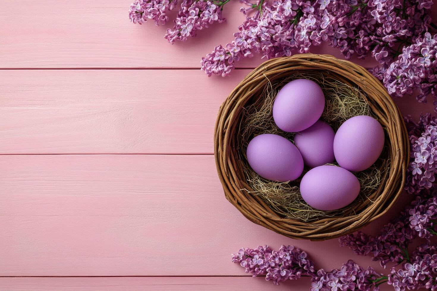 A wicker basket filled with purple eggs surrounded by blooming lilacs on a soft pink table photo
