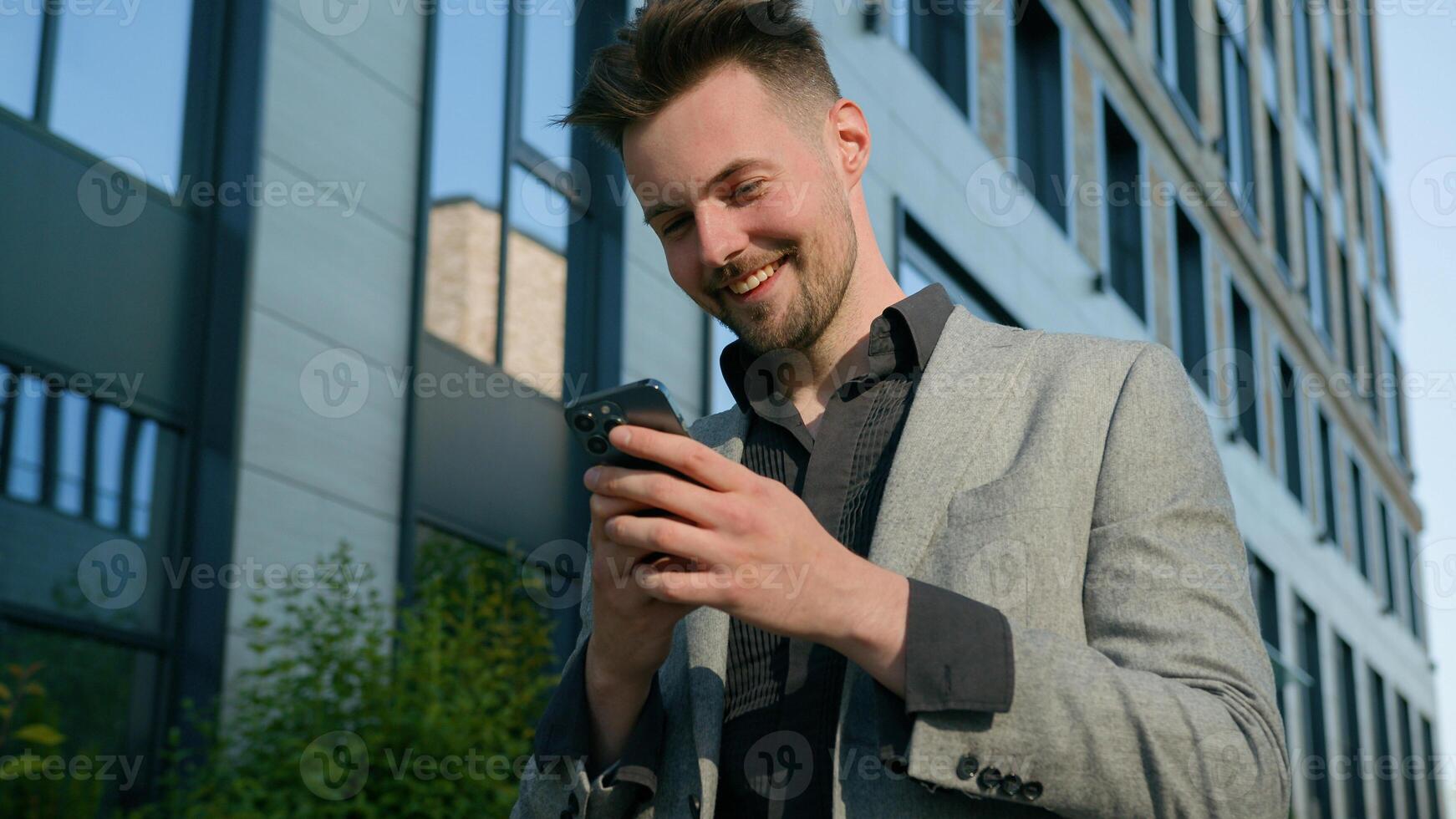 Happy successful caucasian man businessman male guy online winner checking email reading good news using smartphone in city outdoors near office centre enjoying success celebrating victory on phone photo