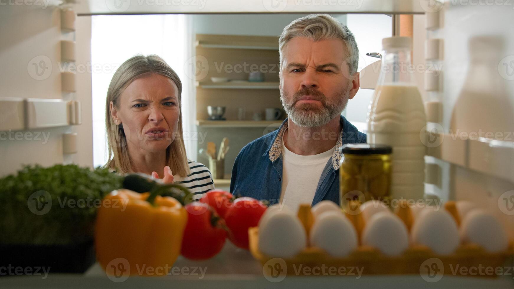 POV Point of view from inside fridge adult couple feeling bad disgusting unpleasant smell from broken refrigerator spoiled rotten food meal middle-aged man and woman awful smelling stink from freezer photo