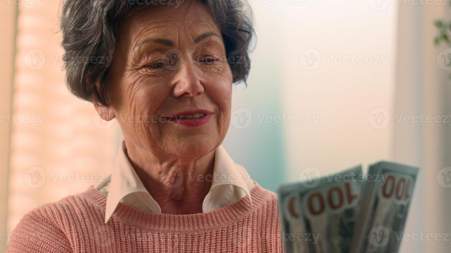Happy smiling rich Caucasian old woman count money at home bills winning bonus grandmother counting dollars senior granny holding cash old female elderly retired lady with banknotes financial savings photo