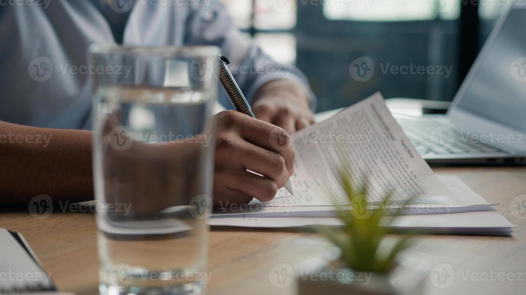 Close up male hands writing exam in class business paperwork with glass of water on office desk unrecognizable man businessman student studying write paper notes document text form insurance summary photo