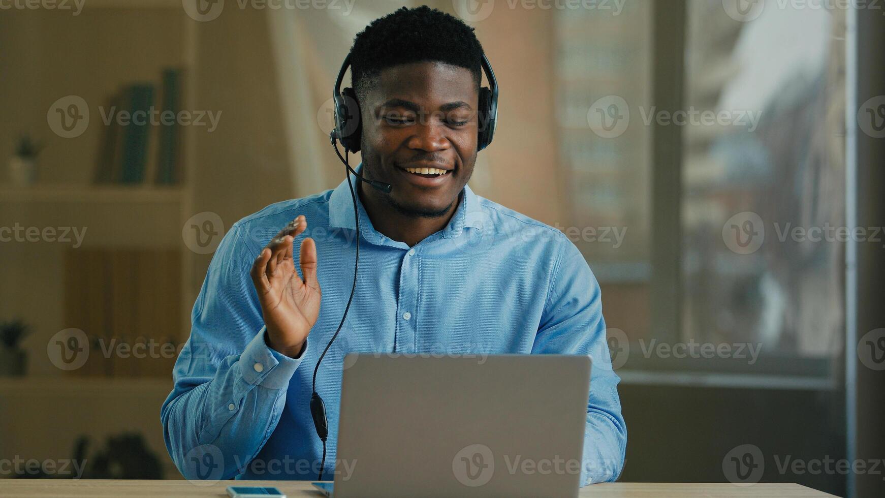 African American ethnic middle-aged man entrepreneur businessman employee helpline operator in headphones computer headset look at web camera speak to client call consultation office briefing photo