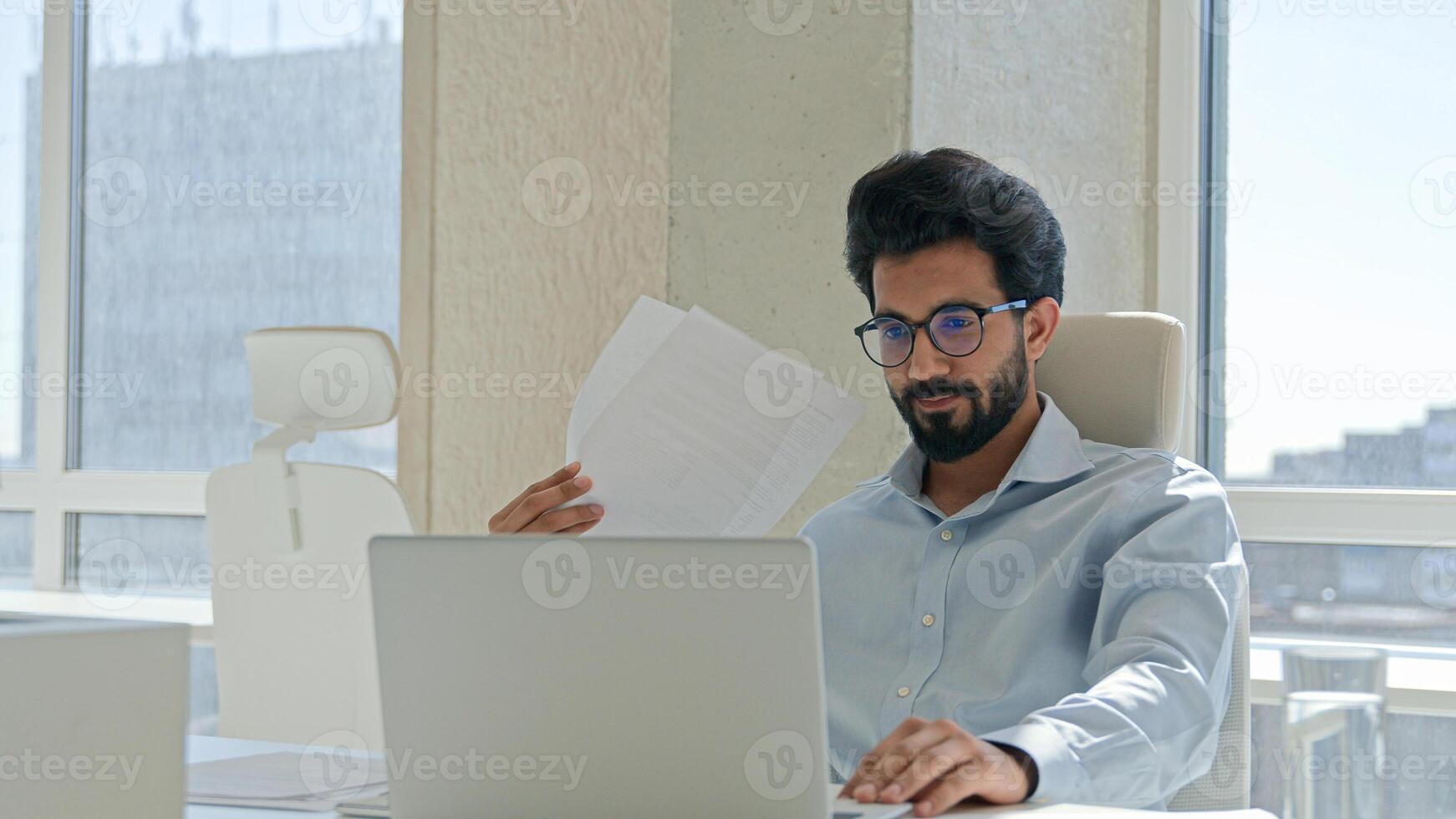 Arabian Indian man tired businessman suffer high temperature uncomfortable heat summer blowing waving papers make wind sit in hot office think project on laptop solve problem broken air conditioner photo