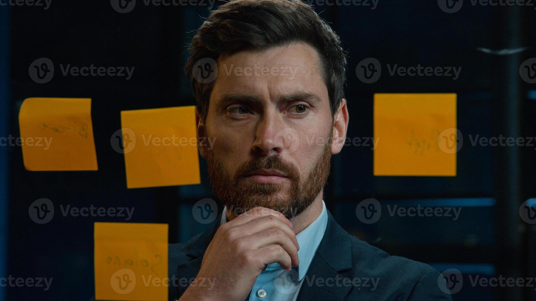 Thoughtful Caucasian businessman employee middle-aged man analyze information on stickers read sticky notes on glass wall standing in office planning project manage tasks startup ideas organizes work photo