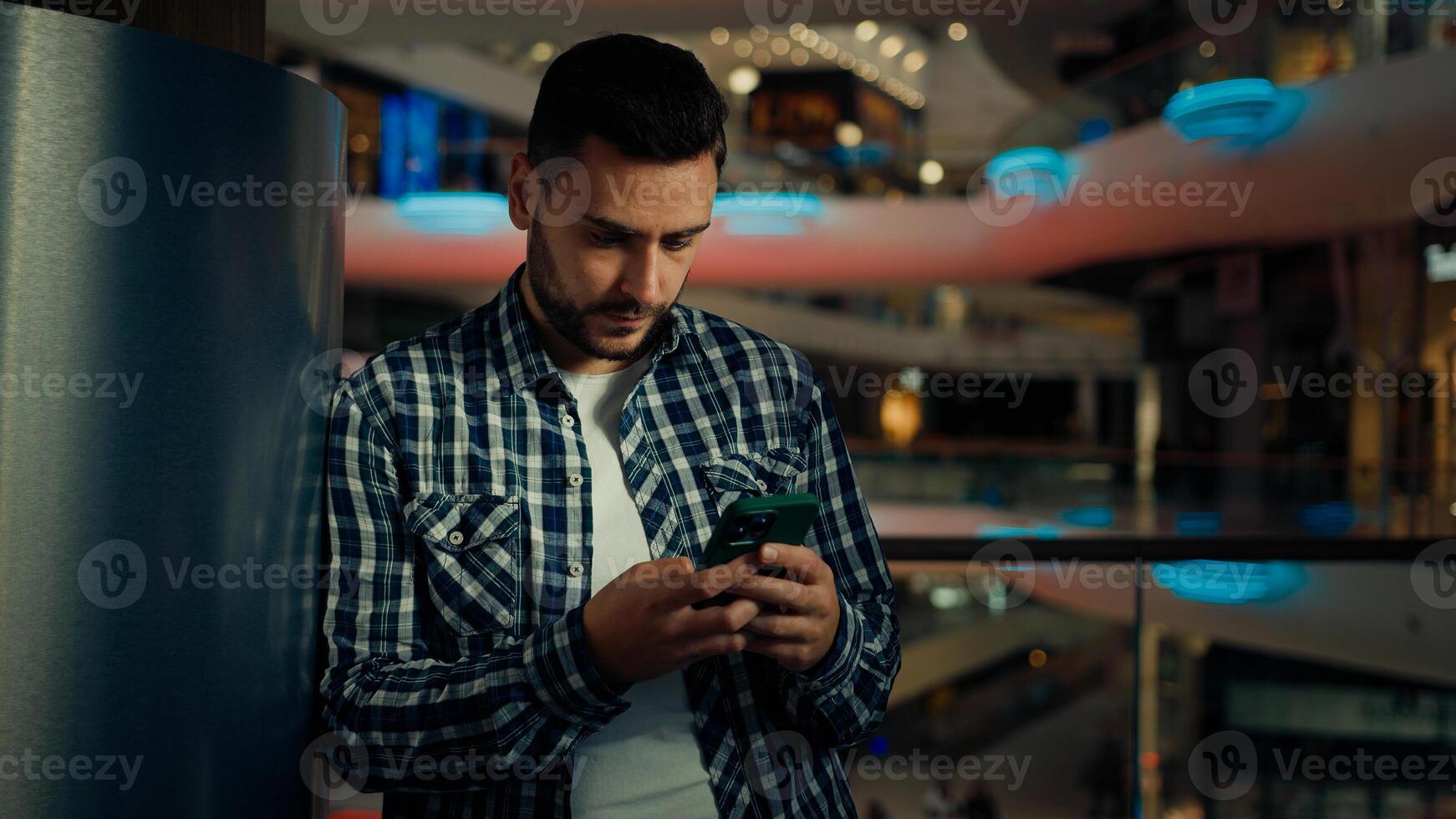 Caucasian hispanic businessman male 30s businessman young man freelancer stand in modern business office chatting online phone wireless communicate use virtual app cyberspace browsing mobile website photo
