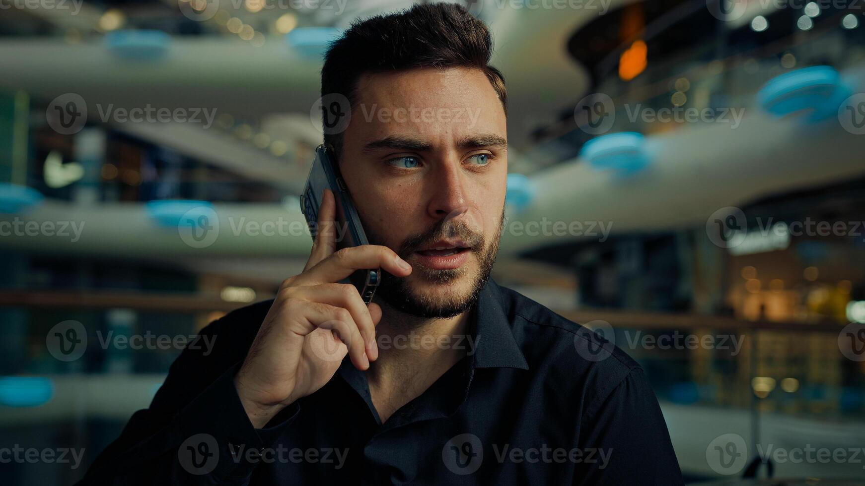 Caucasian hispanic male consultant businessman young man employee speak mobile phone in business company talk mobile phone remote call negotiate cell conversation use telephone smartphone communicate photo