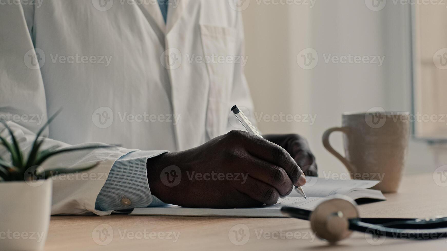 Unrecognizable man doctor therapist cardiologist wears medical coat sit at desk write diagnose in notebook planning work day prescribe medicine results prescription writing professional recommendation photo