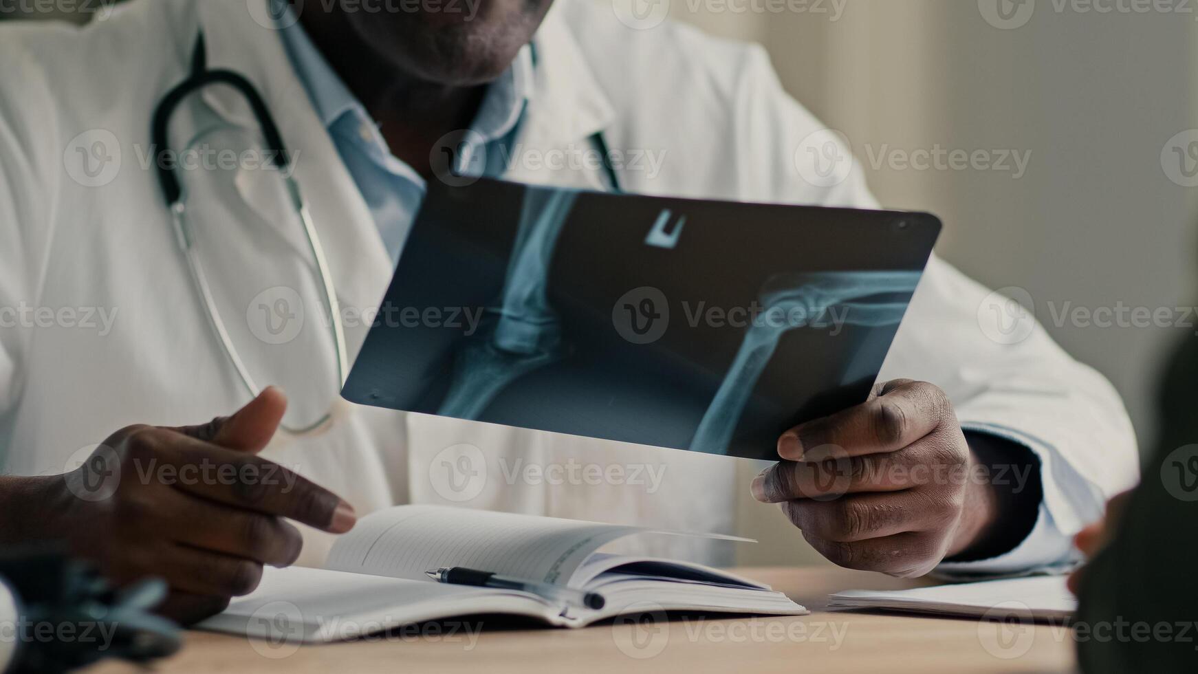 Unrecognizable man doctor african radiologist surgeon therapist osteopath show x-ray scan result MRI tomography roentgen of broken bones joints to patient with trauma surgery consultation in hospital photo