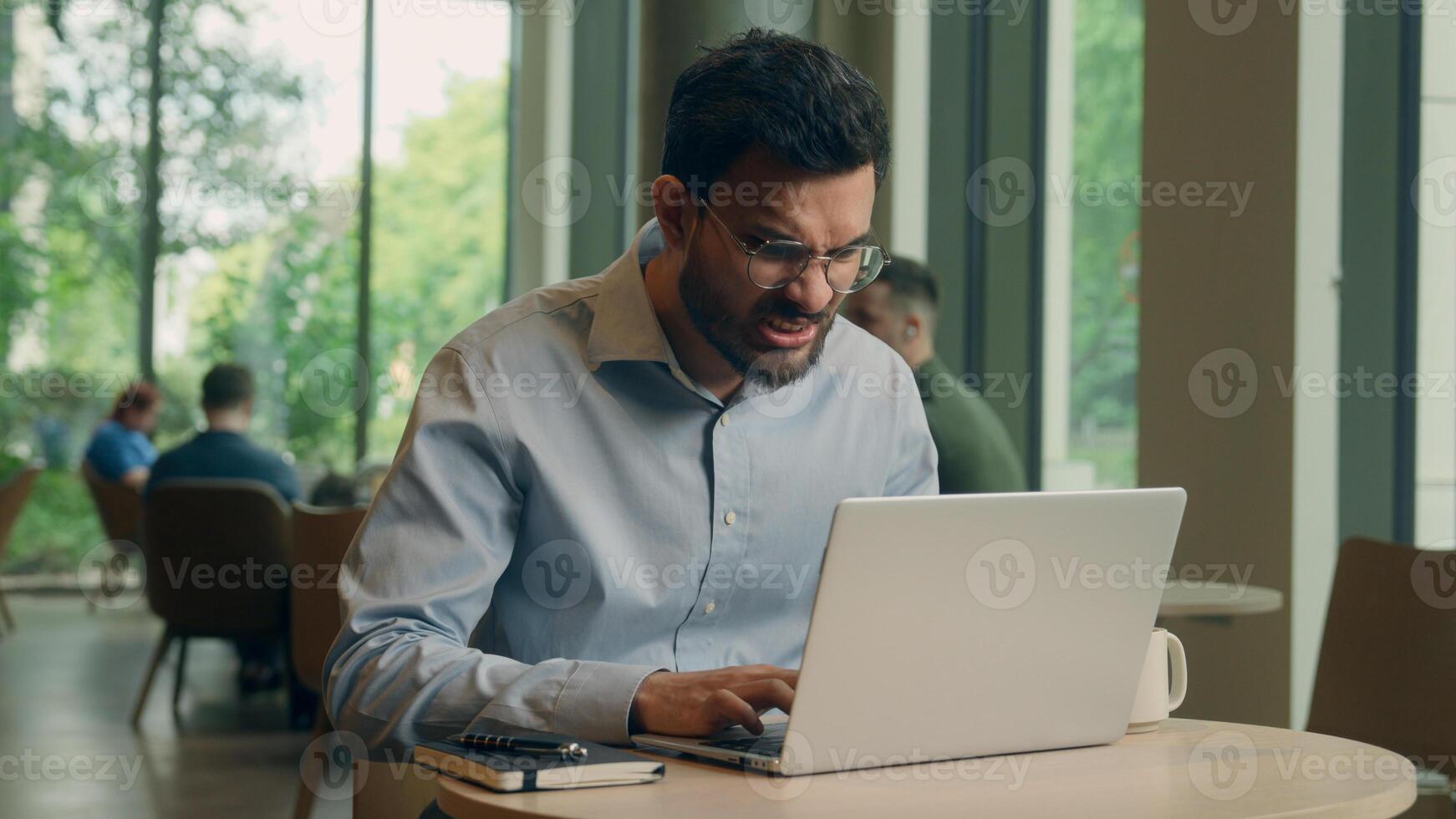 Angry man Arabian Indian male businessman freelancer employee business worker visitor cafe work online laptop computer displeased frustrated worried guy chatting read email deadline fail upset problem photo