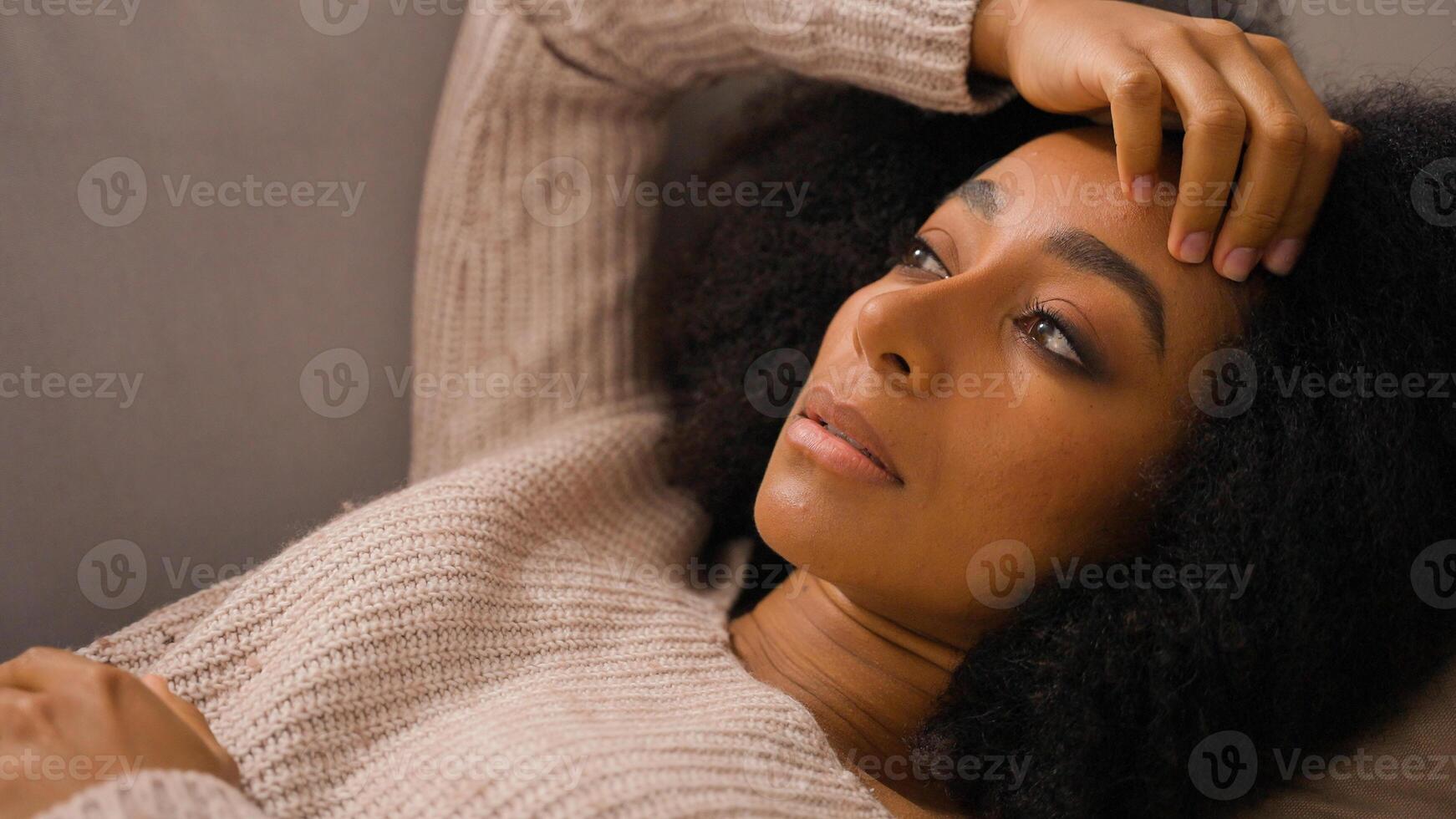 Close up sad despair girl with stress depress lying on couch young African American anxious woman rest on sofa millennial lady suffering from negative thoughts unwanted pregnancy relationship problems photo
