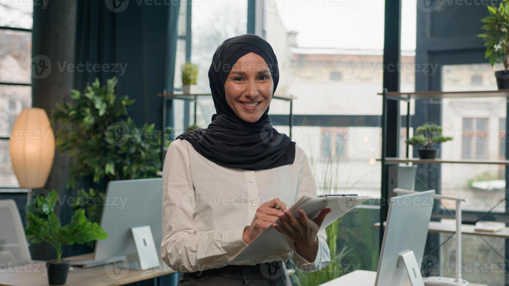 Happy muslim Islam woman Arabian girl in hijab HR manager secretary with paper tablet write notes sign data in note tablet writing to-do list business ideas successful businesswoman planning workflow photo