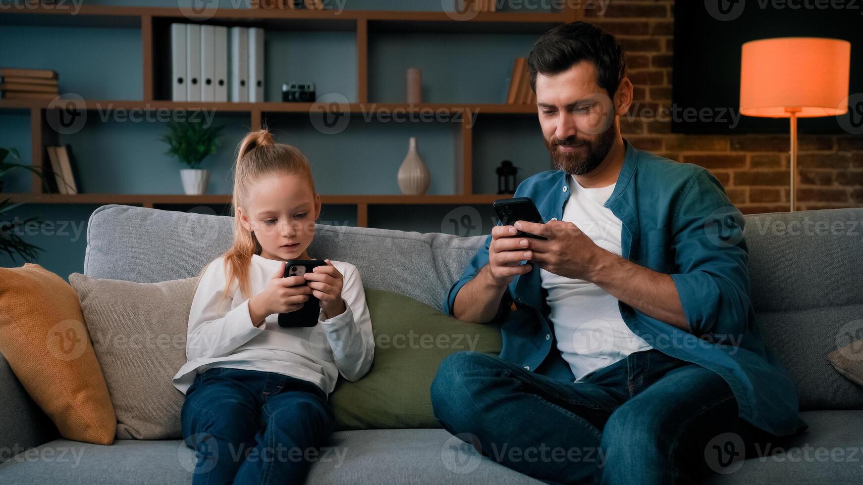 Caucasian single daddy and child kid preschooler girl sit on sofa look at mobile phone screen chatting online use home wifi smartphone apps young family internet addicted modern gadgets tech overuse photo