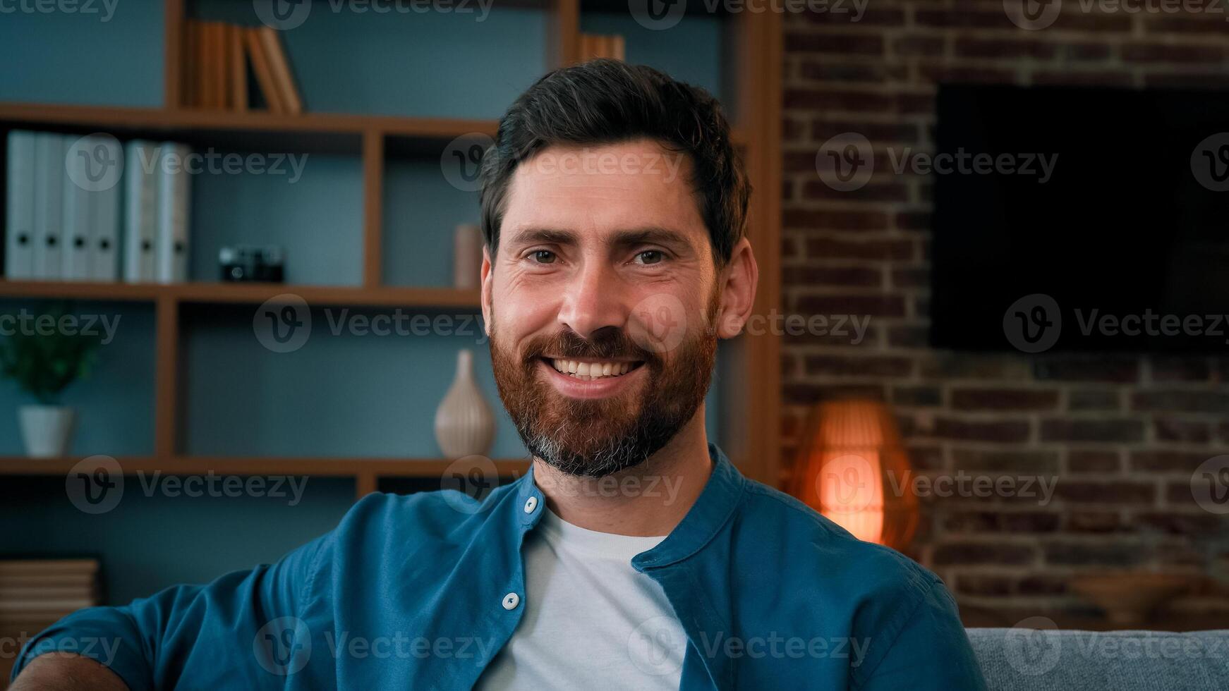 Close up portrait of handsome brunet caucasian man adult happy successful homeowner sit in living room house interior looking at camera smiling male relaxing at home new modern apartment owner concept photo
