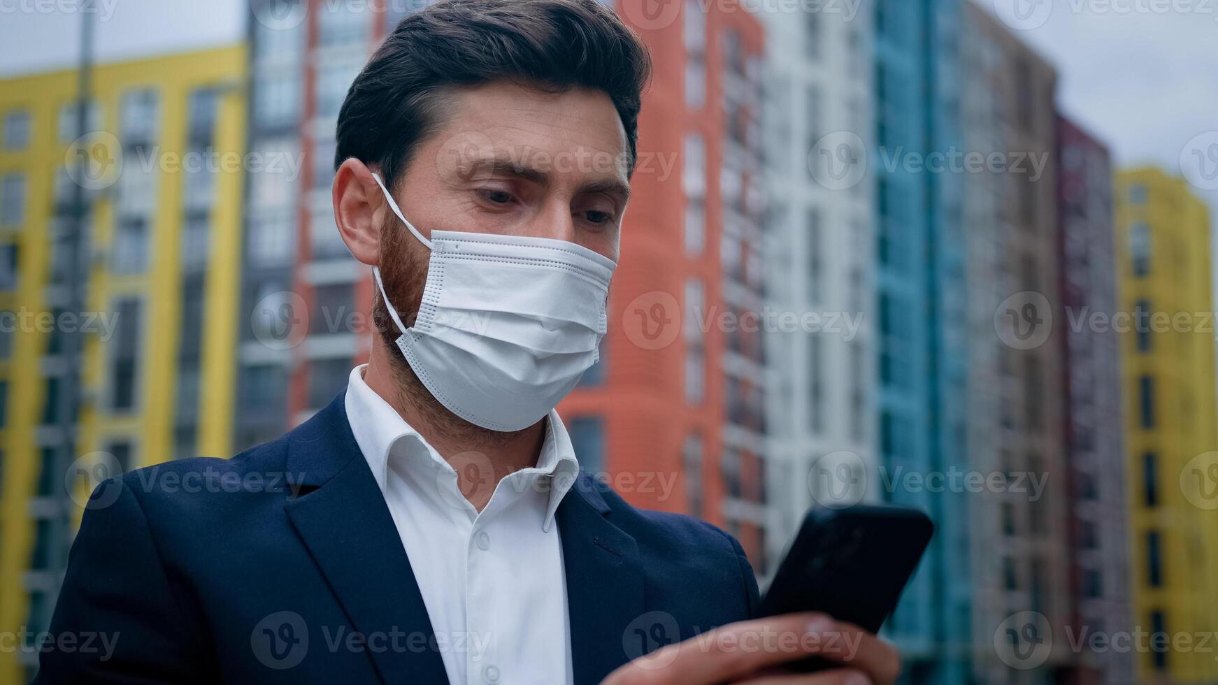 Male businessman in respiratory protection medical mask work on quarantine outdoor texting on smartphone at street professional chat with colleagues online using mobile business apps free wifi outside photo
