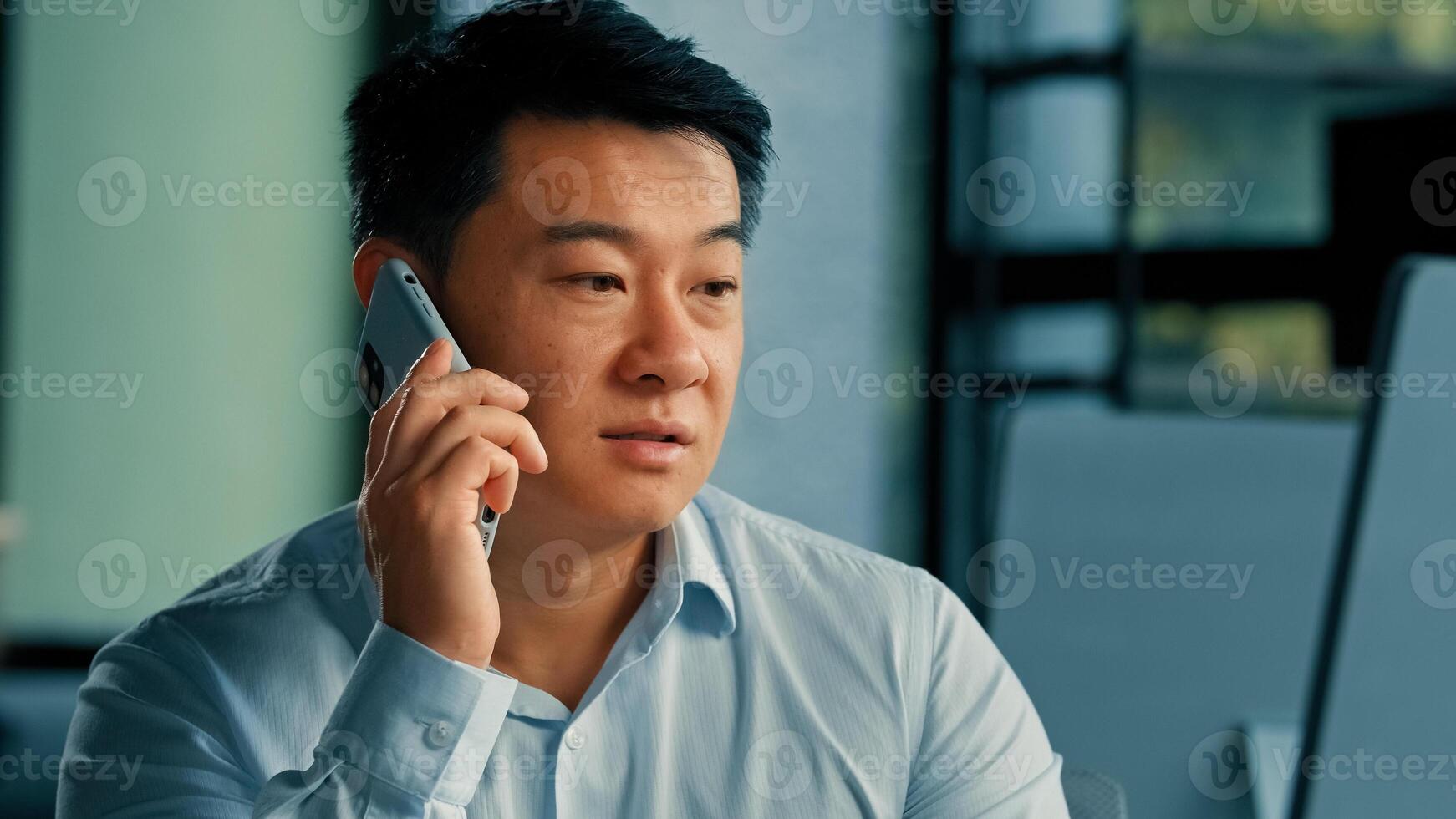 Sad Asian executive worker businessman manager middle-aged korean japanese chinese man answer mobile call work in office speak phone solve business problem distant conversation by 5g cell connection photo