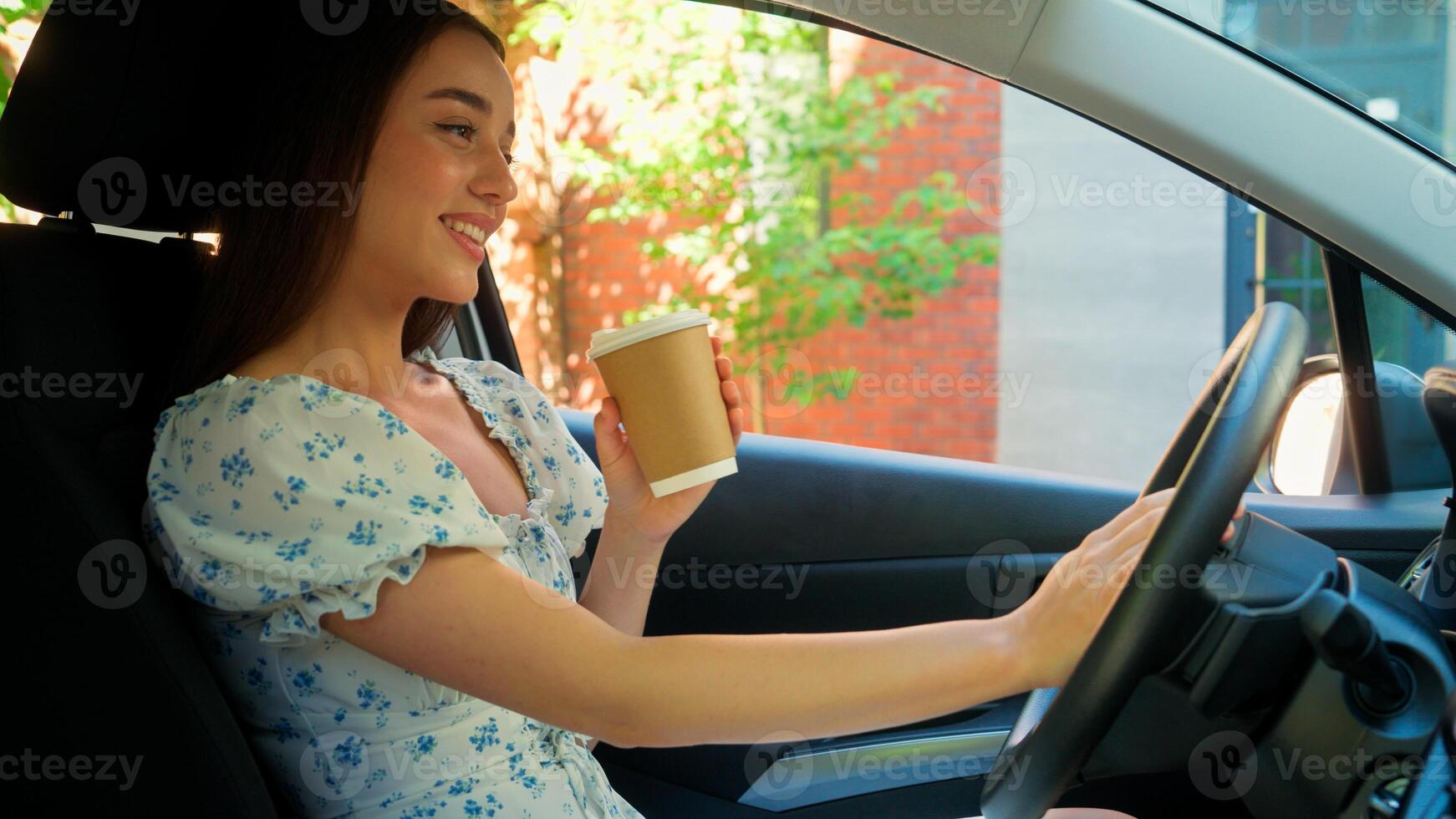 Happy satisfied Caucasian woman driver female client buyer owner girl drinking coffee cup touching car new automobile wheel enjoying morning routine going to work looking at camera smiling inside auto photo