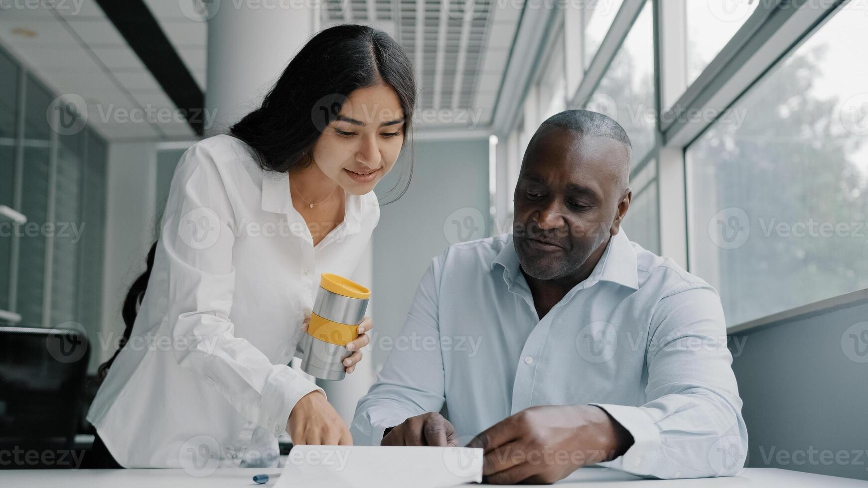 Two colleagues business partners office co-workers analyze paperwork check information. Arabian woman check documentation papers report help african older man with marketing data corporate documents photo