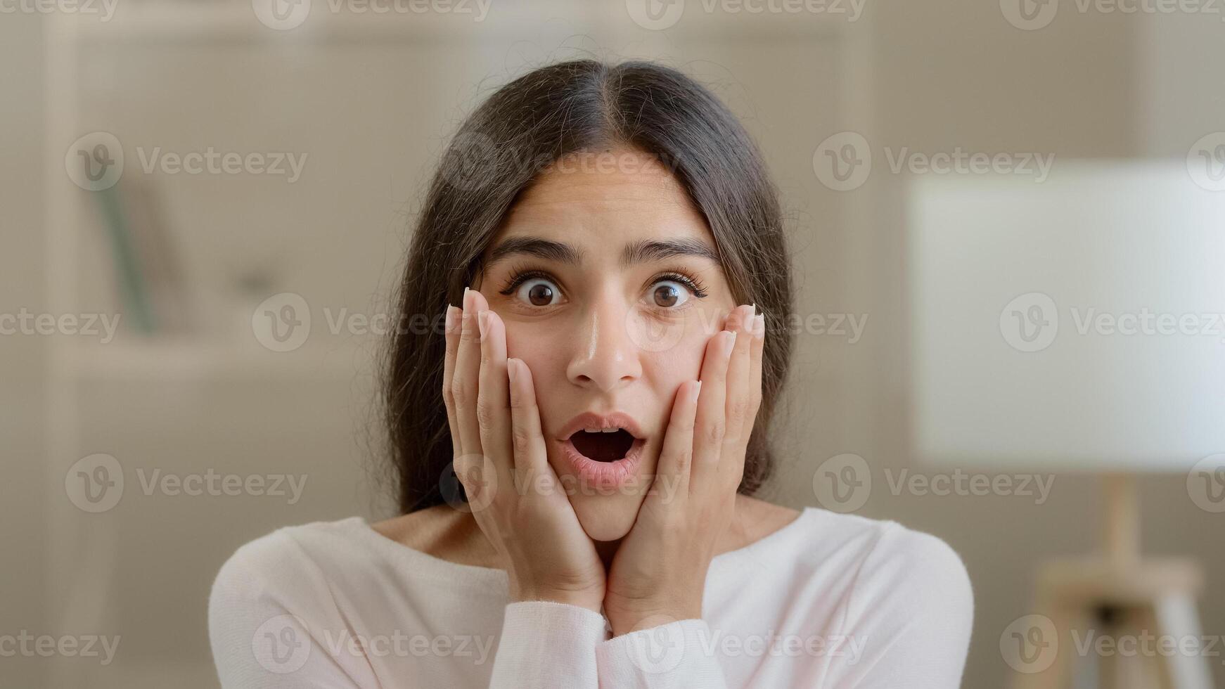 Emotional shocked brunette arab woman stressful frightened scared hispanic girl lady lost hold head with hands feel horror shock receive bad news awful surprise bankruptcy crisis negative information photo