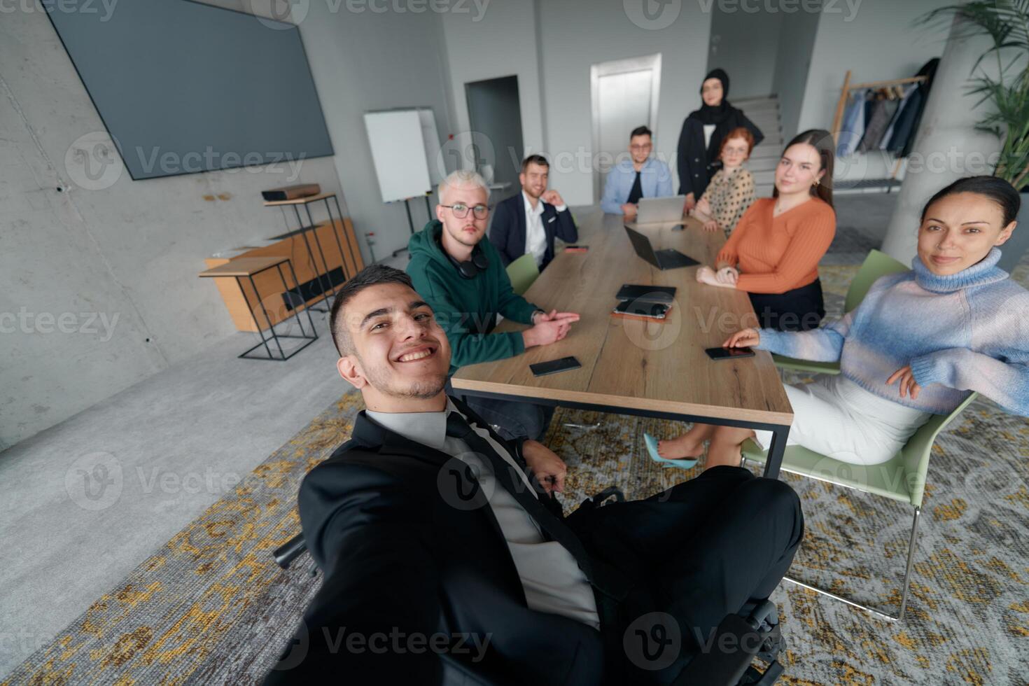 A group of business professionals taking a selfie during a break in an office meeting, capturing a moment of teamwork and collaboration in a modern workplace photo