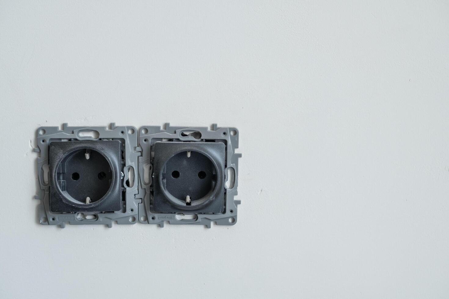 Two empty electrical outlets are installed on a plain white wall, awaiting connection and installation in a new building project photo
