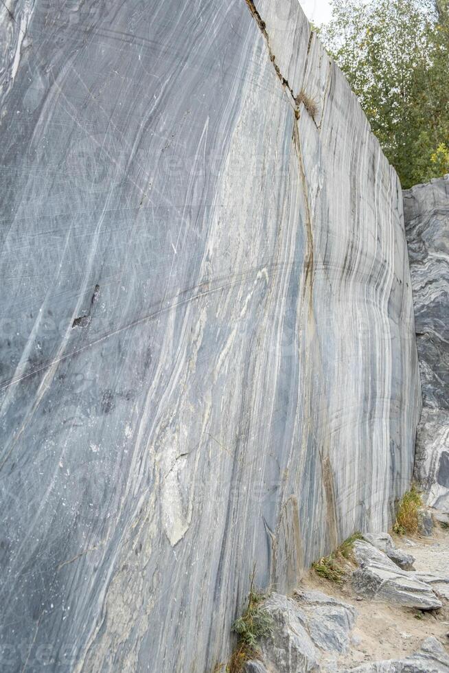 The marble quarry features smooth, polished stone surfaces with natural markings under bright sunlight surrounded by greenery photo