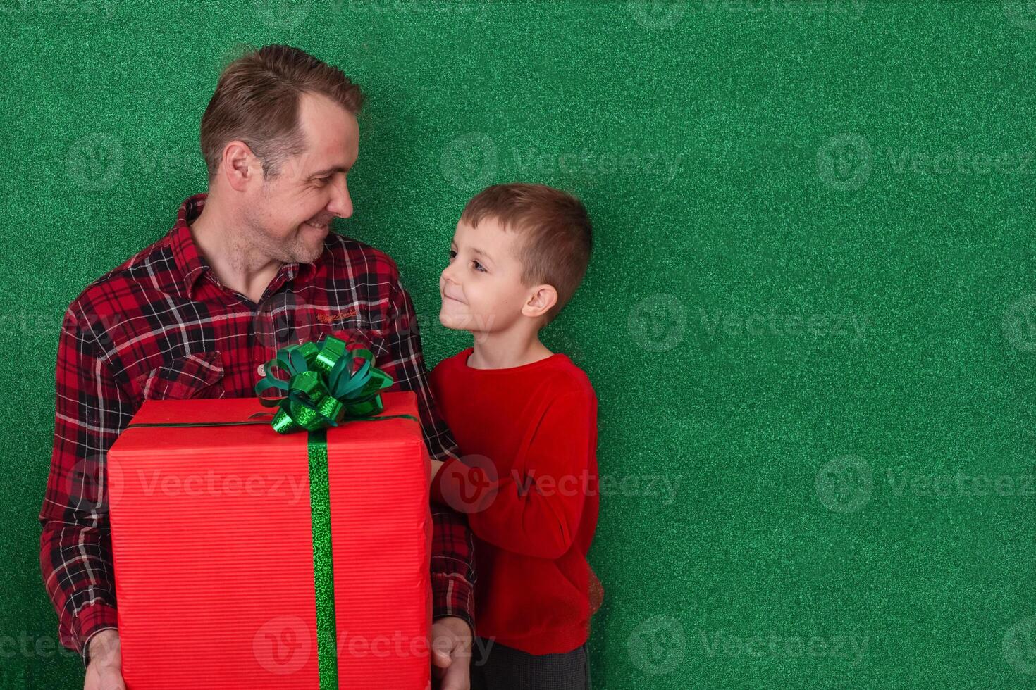 a man with a small son are holding a large gift in cookies on a green background and looking at each other. family congratulations. holidays new year, valentine's day photo