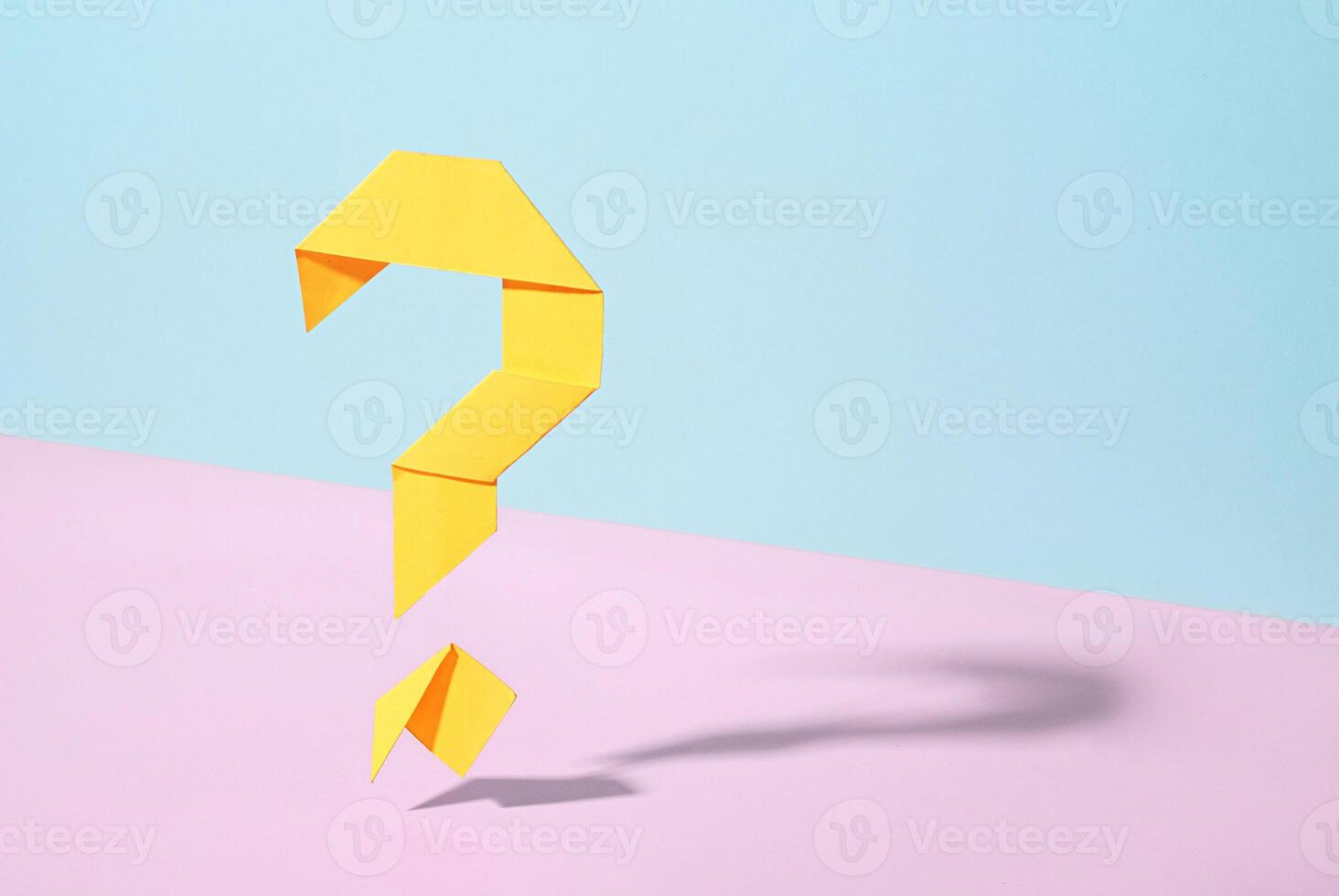 Floating yellow origami question mark on bicolor background photo