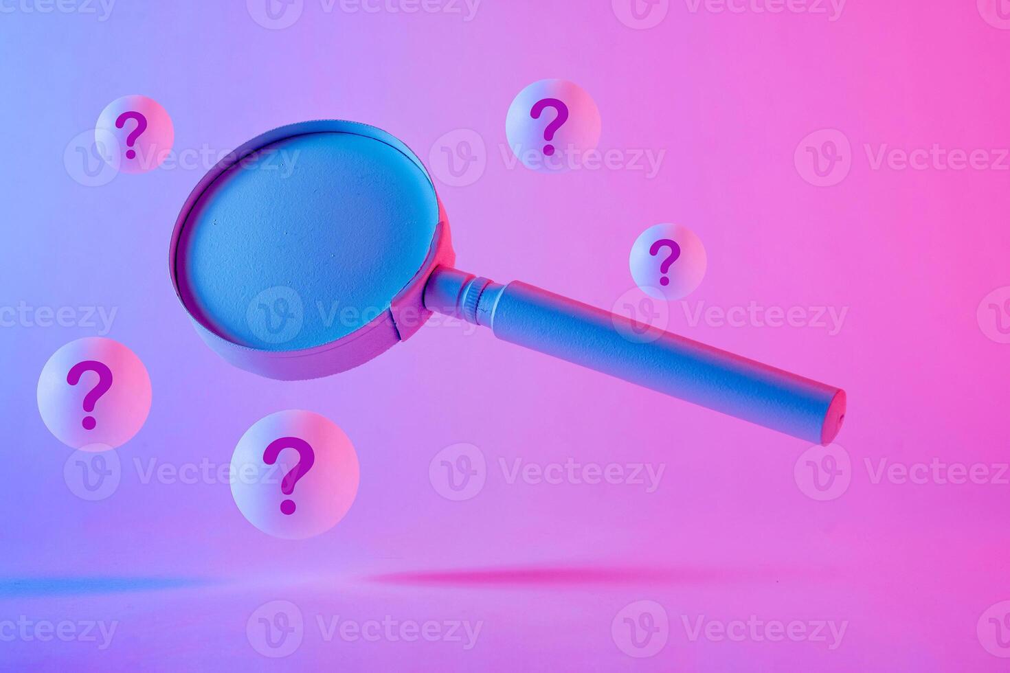 Close-up of a magnifying glass floating between question marks photo