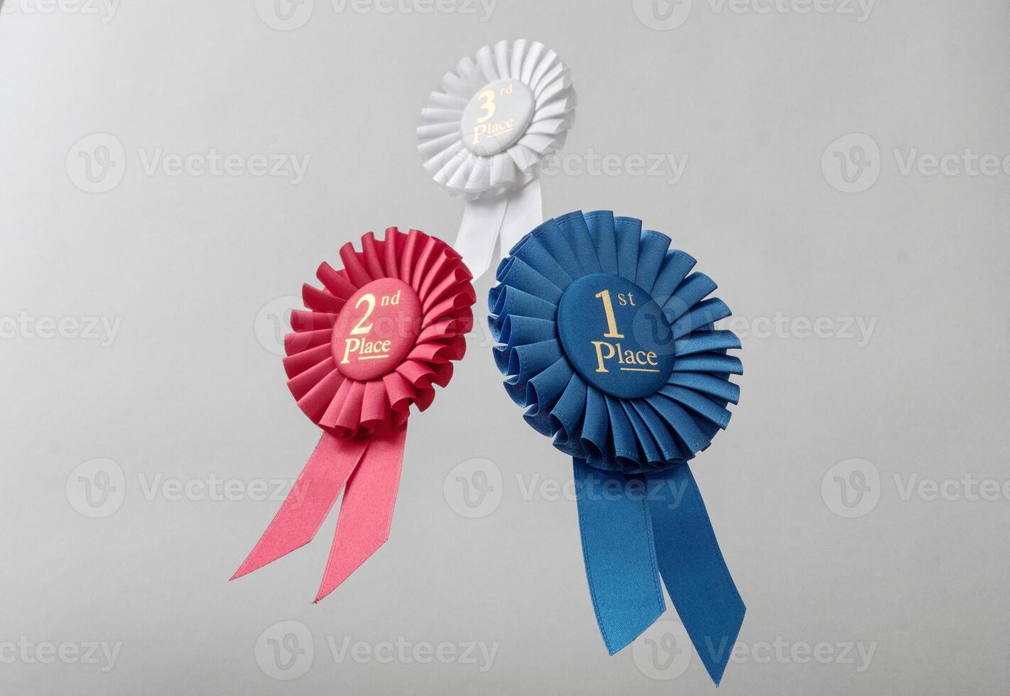 Three rosettes fly over gray background as prizes to winners and champions for quality and victory. photo