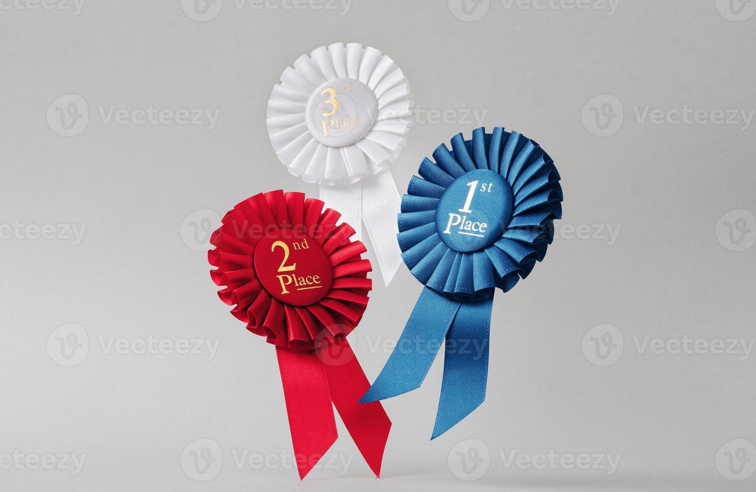 Three rosettes fly over gray background as awards to winners and champions for success and victory. photo