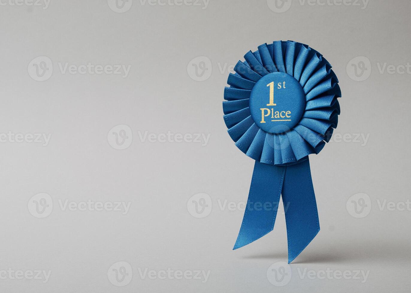 Blue rosette first place on a gray background as a reward for achievement, success and victory. photo
