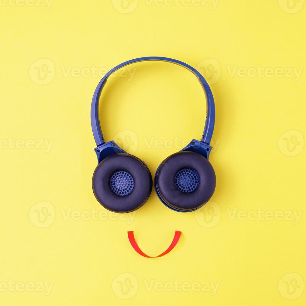 Headphones on a yellow background in the form of a happy face with a smile - Minimalistic composition with a concept about music or a disco or learning in audio photo