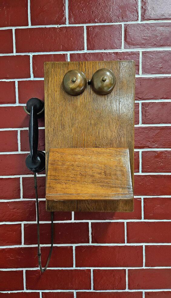 Vintage wooden telephone hanging on brick wall. Telecommunication device on background. Brown object, Old technology or vintage for calling and phone to people. photo