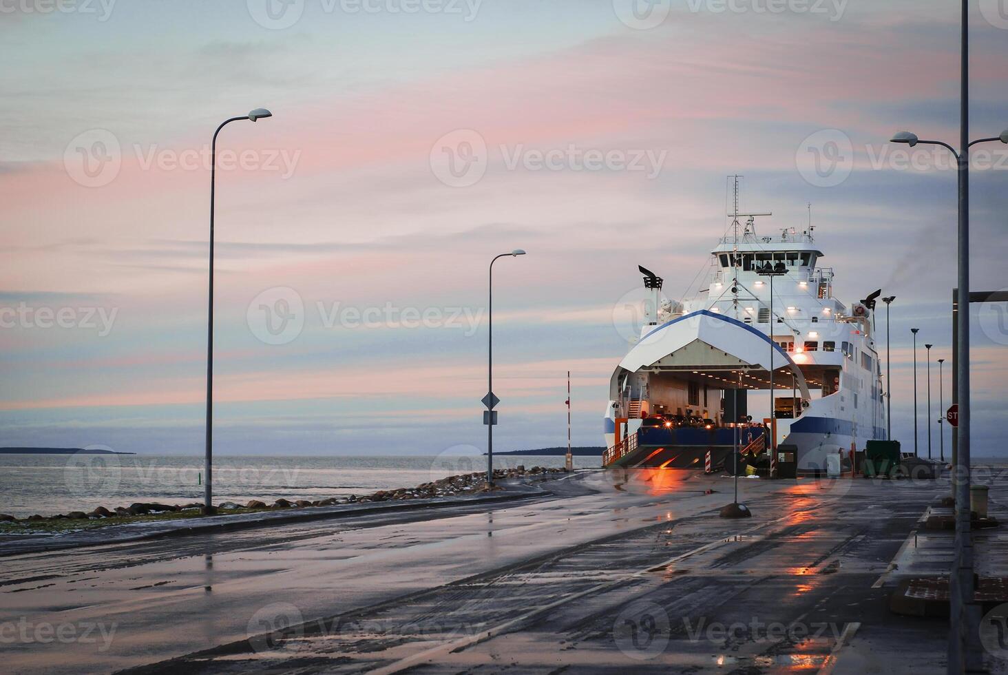 Ferry at dock with colorful sunset sky reflecting on wet pavement photo