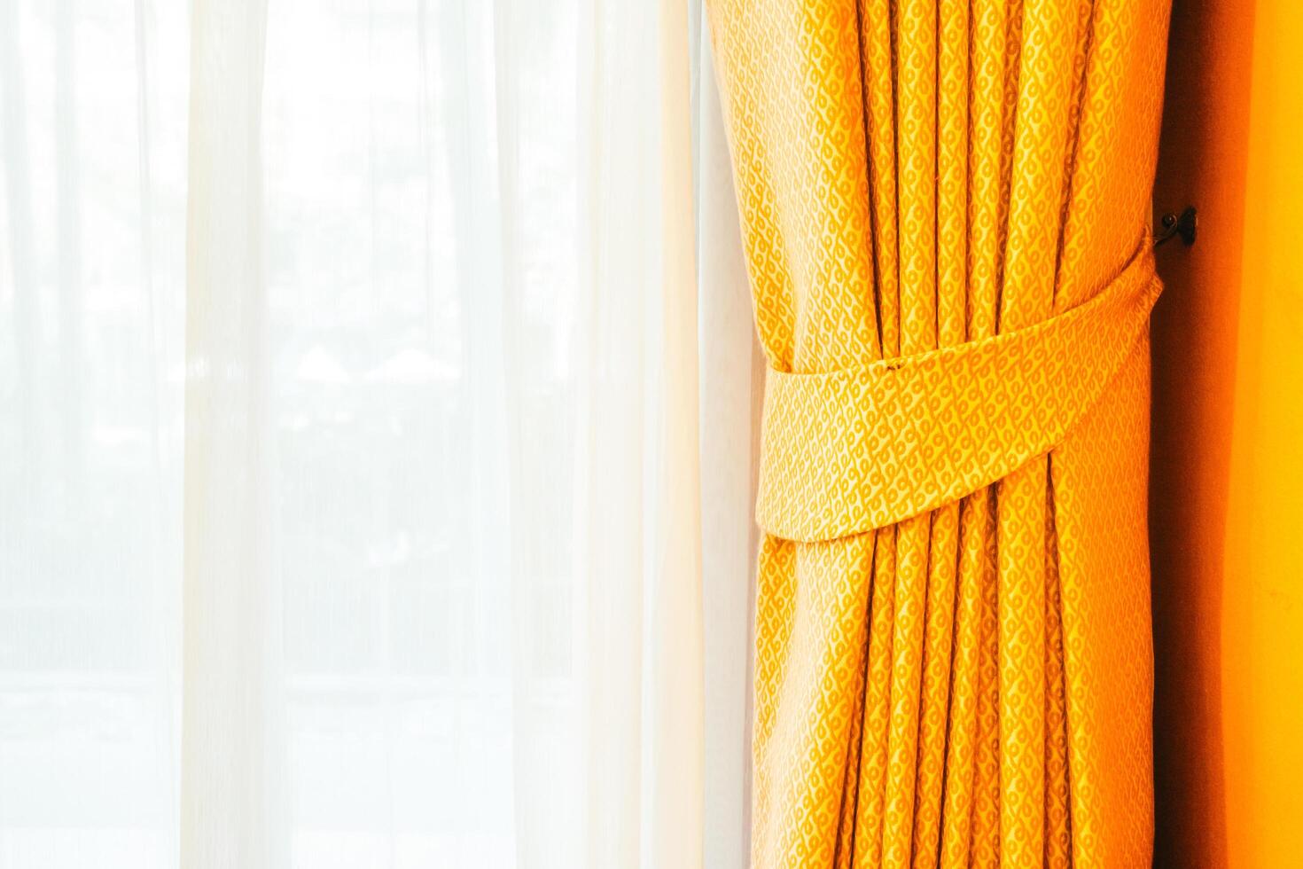 A yellow curtain with a white curtain behind it photo