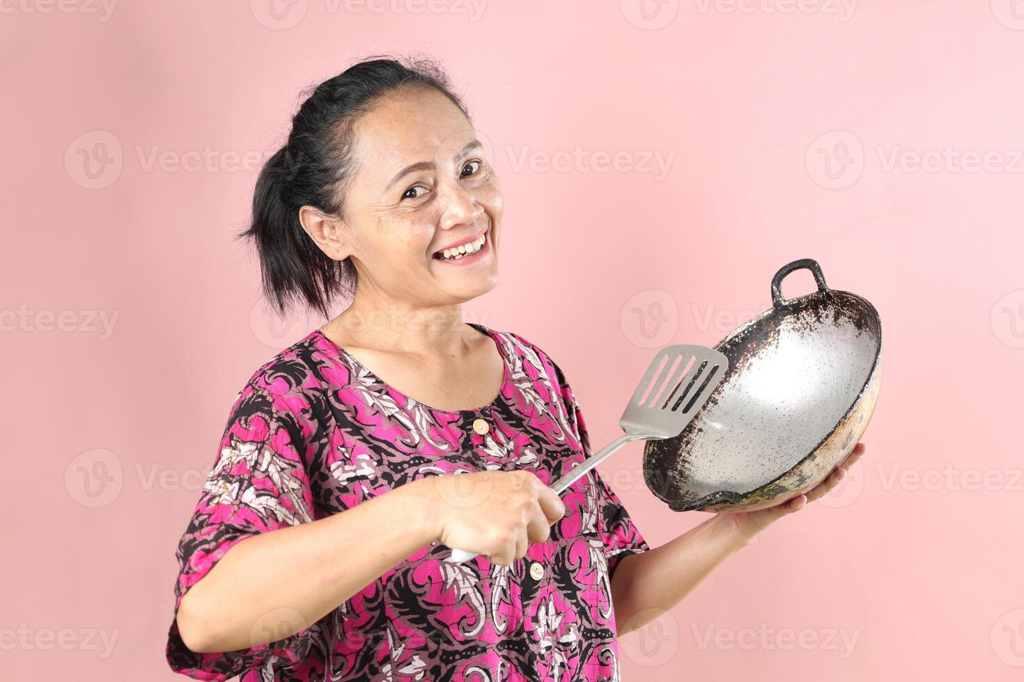 Indonesian Mom Holding Cooking Appliance, Wajan Frying Pan and Slotted Spatula. photo