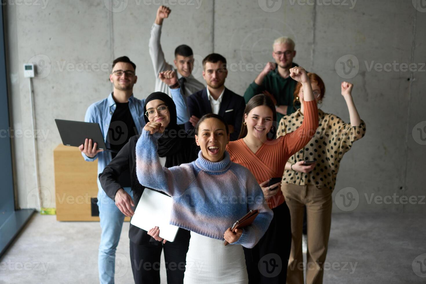 A diverse team of business professionals ecstatically celebrating their success in a modern office, expressing triumph and unity after achieving their goals photo
